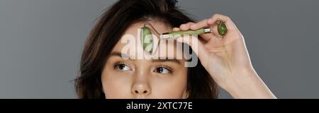 Eine Frau massiert ihre Stirn mit einer Jaderolle. Stockfoto