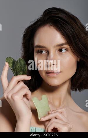 Eine Frau hält zwei Jade-Gua-Sha-Werkzeuge in der Hand. Stockfoto