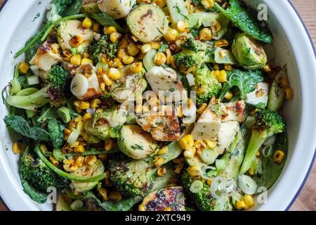 Ein verkohltes frisches Gemüsegericht mit rosenkohl, gegrilltem Käse, Brokkoli-Stielen, Zuckermais, zerstoßenen Nüssen und Dressing. Stockfoto