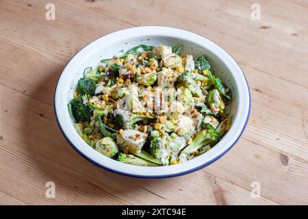 Ein verkohltes frisches Gemüsegericht mit rosenkohl, gegrilltem Käse, Brokkoli-Stielen, Zuckermais, zerstoßenen Nüssen und Dressing. Stockfoto