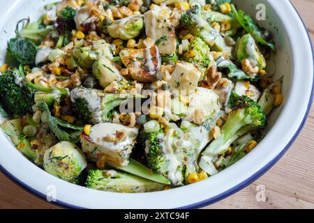 Ein verkohltes frisches Gemüsegericht mit rosenkohl, gegrilltem Käse, Brokkoli-Stielen, Zuckermais, zerstoßenen Nüssen und Dressing. Stockfoto