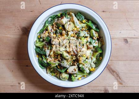 Ein verkohltes frisches Gemüsegericht mit rosenkohl, gegrilltem Käse, Brokkoli-Stielen, Zuckermais, zerstoßenen Nüssen und Dressing. Stockfoto