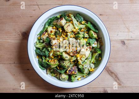 Ein verkohltes frisches Gemüsegericht mit rosenkohl, gegrilltem Käse, Brokkoli-Stielen, Zuckermais, zerstoßenen Nüssen und Dressing. Stockfoto