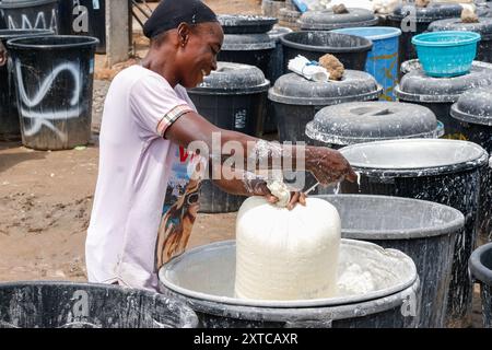 Die Weibchen in Abuja kämpfen in einer lokalen Maniok-Verarbeitungsfabrik unter schwierigen Bedingungen, um Mehl herzustellen, während sie die Spreu aus fermentiertem Maniok waschen. Angesichts der wirtschaftlichen Unsicherheiten stehen diese jungen Mädchen und Frauen vor verschiedenen Herausforderungen, um sich selbst zu stärken, Arbeitsplätze für andere zu schaffen und den Lebensunterhalt zu sichern. Die meisten Frauen hier sind Brotgewinner und sie kämpfen für ihre Familien. Nigeria. Stockfoto