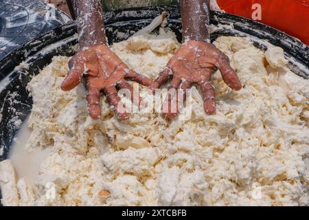 Die Weibchen in Abuja kämpfen in einer lokalen Maniok-Verarbeitungsfabrik unter schwierigen Bedingungen, um Mehl herzustellen, während sie die Spreu aus fermentiertem Maniok waschen. Angesichts der wirtschaftlichen Unsicherheiten stehen diese jungen Mädchen und Frauen vor verschiedenen Herausforderungen, um sich selbst zu stärken, Arbeitsplätze für andere zu schaffen und den Lebensunterhalt zu sichern. Die meisten Frauen hier sind Brotgewinner und sie kämpfen für ihre Familien. Nigeria. Stockfoto