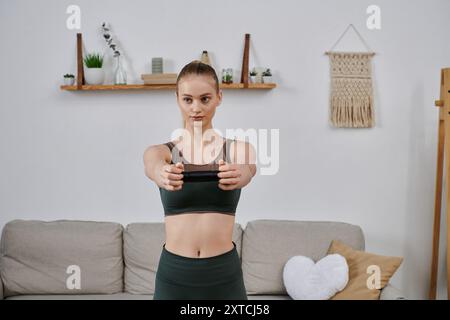 Eine junge Frau in Sportkleidung führt eine Widerstandsbandübung in ihrem Wohnzimmer durch. Stockfoto