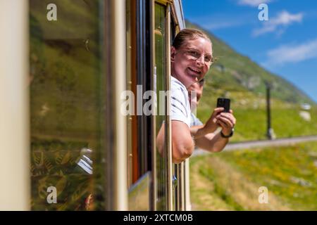Zugpassagiere mit dem Alpine Classic Pullman Express am Oberalp-Pass in 2.000 Metern Höhe machen Fotos von der Kutsche auf der nostalgischen Fahrt von Davos nach Andermatt. Alpine Classic Pullman Express auf der Route des Glacier Express, URI, Schweiz Stockfoto