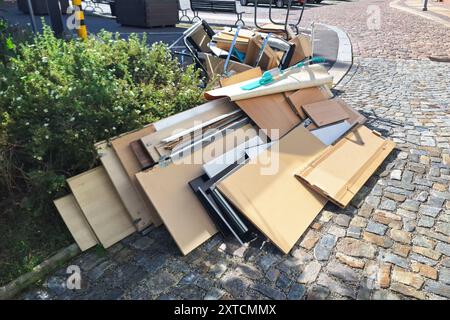 Ein Haufen aussortierter Haushaltsgegenstände und Möbel, die auf einer kopfsteingepflasterten Straße aufgehäuft sind und einen Tag der Müllsammlung in einer Stadt darstellen Stockfoto