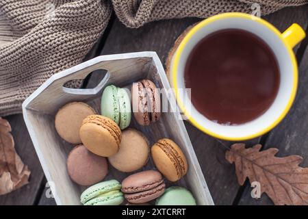 Eine Tasse heißer Kakao, Makronen, ein Strickpullover auf einem Holztisch. Herbst. Gemütlich. Stockfoto