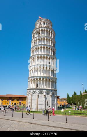 Vertikale Aufnahme des isolierten Schiefen Turms von Pisa in der Toskana, Italien mit einigen Touristen im Vordergrund. Stockfoto