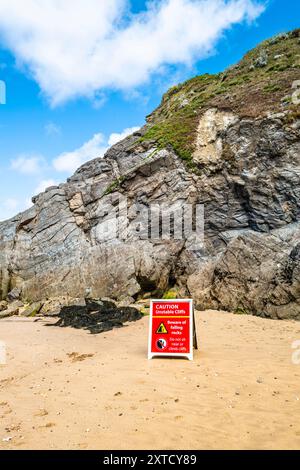 Ein Gefahrenschild, das vor instabilen Klippen und herabfallenden Felsen am Strand unterhalb der Klippen am GT Great Western Beach in Newquay in Cornwall in Großbritannien warnt. Stockfoto