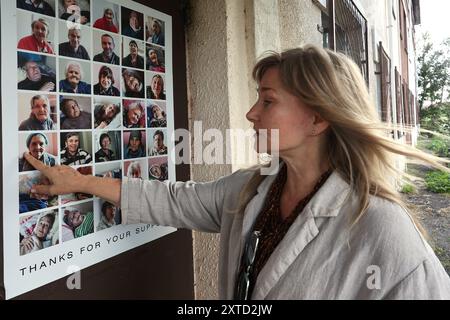 KHARKIW, UKRAINE - 13. AUGUST 2024 - durch den Krieg zeigt die NGO-Vorsitzende Olha Kleitman die Fotos des Wohnsitzes der Big Family, das sich um allein lebende ältere Menschen kümmert, die durch den Krieg obdachlos wurden und von ihrer Organisation Charkiw, Nordostukraine, geführt wird. Stockfoto