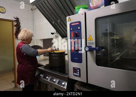 CHARKIW, UKRAINE - 13. AUGUST 2024 - ein Mitarbeiter kocht im Big Family Shelter, das sich um allein lebende ältere Menschen kümmert, die durch den Krieg obdachlos geworden sind und von der NRO Charkiw, Nordost-Ukraine, geführt wird. Stockfoto