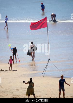 Sicherheitsabschaltung für Tausende von Besuchern. RNLI Rettungsschwimmer ergreifen eine unbeliebte, aber notwendige Maßnahme, indem sie Schwimmer und Surfer raten, das Wasser zu räumen. Obwohl der beliebte Strand, der für seine Heimat des britischen Surfens berühmt ist, von Ende zu Ende mit rekordverdächtigen Menschenmengen überfüllt ist, führte eine Entscheidung angesichts der großen, rauen Wellenbedingungen in Kombination mit einer ausgehenden Flut dazu, dass die Red Flags gehisst wurden, um zu verhindern, dass die Leute in Schwierigkeiten geraten. In den vergangenen Tagen fanden im Resort eine Reihe von größeren Rettungsaktionen am Strand statt, darunter 200 Menschen, die aus Whipsiderr evakuiert wurden Stockfoto