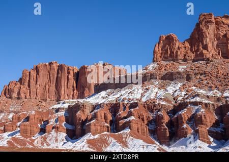 Atemberaubende Winterlandschaft mit den legendären roten Felsformationen des Capitol Reef National Park in Utah, die unter einem klaren blauen Himmel mit Schnee bedeckt sind Stockfoto