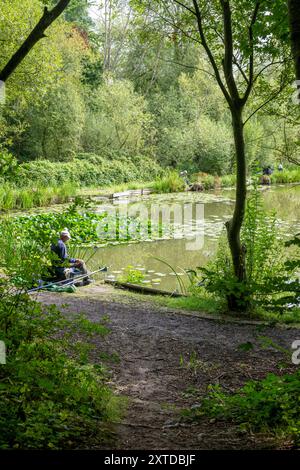 Einige Männer fischen im Sommer von künstlich hergestellten Pegs und Plattformen in einem Pool, der von Bäumen und Vegetation umgeben ist Stockfoto