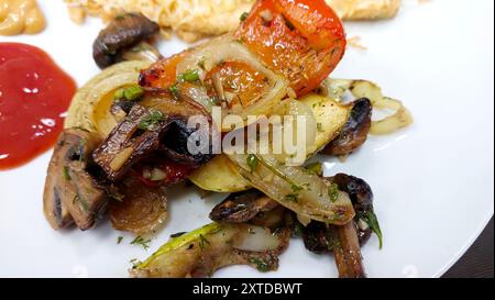Eine bunte Auswahl an gegrilltem Gemüse und Pilzen wird zusammen mit einer Portion Ketchup für zusätzlichen Geschmack serviert. Stockfoto