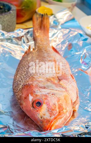 Nahaufnahme eines roten Schnappfisches auf Aluminiumfolie, bereit zum Kochen. Stockfoto