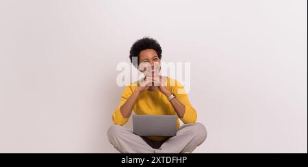 Porträt eines lächelnden, schönen Unternehmers mit gefalteten Händen und Laptop auf weißem Hintergrund Stockfoto