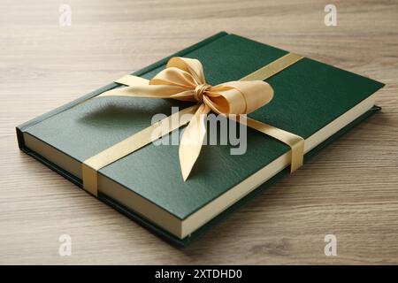 Buch gebunden mit goldenem Band auf Holztisch, Großaufnahme Stockfoto