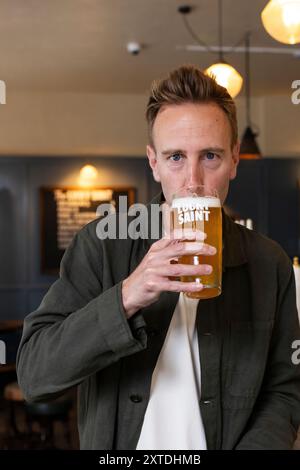 Luke Boase, Gründer und CEO der alkoholfreien Biermarke Lucky Saint, fotografierte mit seinem alkoholfreien Bier in einem Londoner Pub in England, Großbritannien Stockfoto