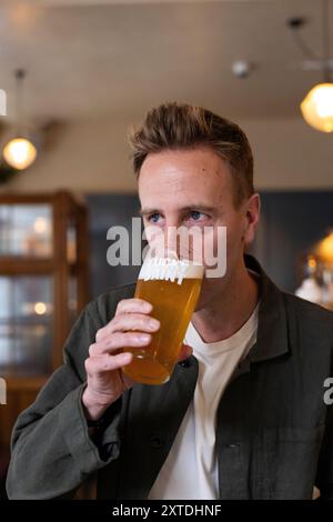 Luke Boase, Gründer und CEO der alkoholfreien Biermarke Lucky Saint, fotografierte mit seinem alkoholfreien Bier in einem Londoner Pub in England, Großbritannien Stockfoto