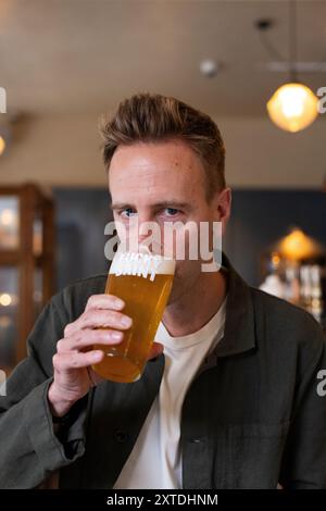 Luke Boase, Gründer und CEO der alkoholfreien Biermarke Lucky Saint, fotografierte mit seinem alkoholfreien Bier in einem Londoner Pub in England, Großbritannien Stockfoto