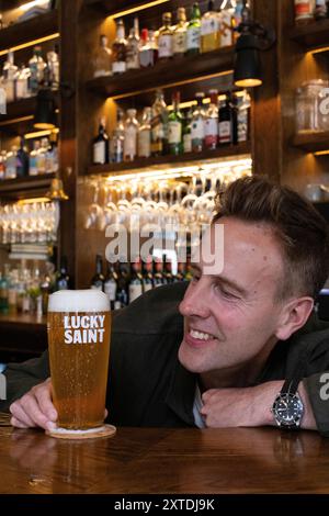 Luke Boase, Gründer und CEO der alkoholfreien Biermarke Lucky Saint, fotografierte mit seinem alkoholfreien Bier in einem Londoner Pub in England, Großbritannien Stockfoto