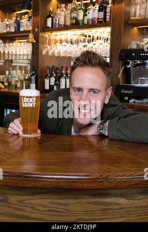 Luke Boase, Gründer und CEO der alkoholfreien Biermarke Lucky Saint, fotografierte mit seinem alkoholfreien Bier in einem Londoner Pub in England, Großbritannien Stockfoto