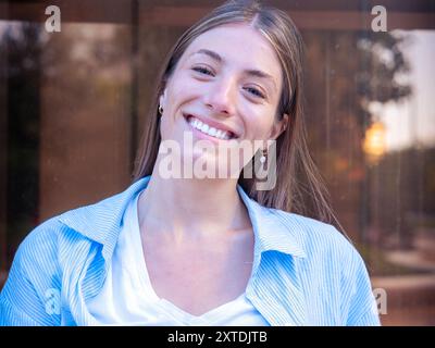 Junge kaukasische Frau lächelt selbstbewusst auf der Straße. Stockfoto