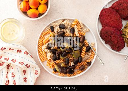 Genießen Sie ein köstliches vegetarisches Gericht mit glutenfreier Pasta mit gebackenen Bohnen und Zucchini, begleitet von Rübenpfannkuchen mit Sonnenblumenkorn-Hummus. Ein Vorteil Stockfoto