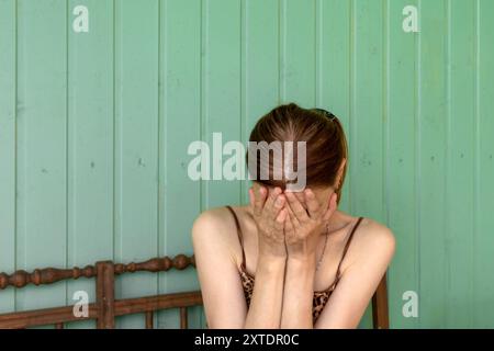 Eine nicht erkennbare junge Frau bedeckte ihr Gesicht mit ihren Handflächen und drückte Verzweiflung und Trauer aus. Kopierbereich. Stockfoto