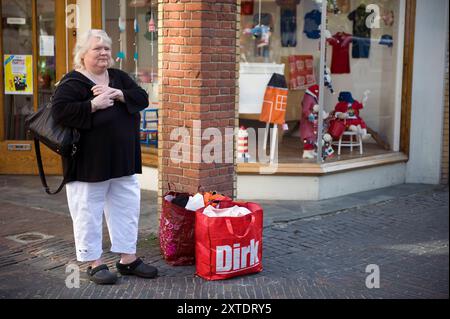 Porträt-Frau mit Einkaufstaschen Reife Erwachsene, Kaukasierin mit Einkaufstaschen, die auf ihre Heimfahrt nach einem Einkaufsbummel warten, in der Innenstadt von Utrecht, Niederlande. Utrecht Binnenstad, Springweg Utrecht Nederland Copyright: XGuidoxKoppesxPhotox Stockfoto