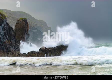 Mächtige Wellen prallen auf felsige Klippen und erzeugen im Sommer eine atemberaubende Schauspiel von Spritzwasser und Schauspiel entlang der Isle of Lewis. Stockfoto