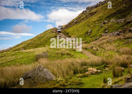 Eine kleine Gruppe von Geländewagen fährt einen steilen, grasbewachsenen Hügel in den Yorkshire Dales hinab und erkundet die natürliche Schönheit der Landschaft. Stockfoto