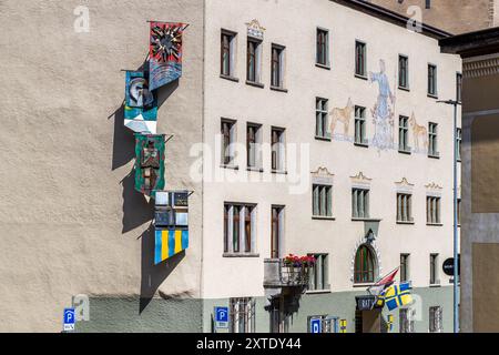 Die Fassade des Davoser Rathauses ist mit vier Fahnen von Herman Kloeckler verziert. Die Sonne symbolisiert die Heilkraft des Kurortes. Der Steinbock symbolisiert Graubünden, der Wilde der Zehntbund und das Wappen die Landschaft von Davos. Oberwiesstraße, Davos, Graubünden, Schweiz Stockfoto