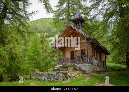 Die malerische Kapelle von Planchouet steht friedlich inmitten von Grün und spiegelt die harmonische Mischung aus Architektur und Natur in den Schweizer Alpen wider. Stockfoto