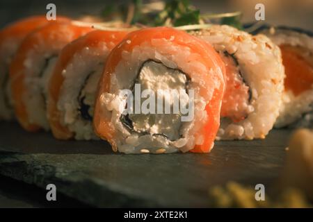 Ein Sushi-Brötchen mit weichem Käse. Die Rolle ist auf einer schwarzen Platte Stockfoto