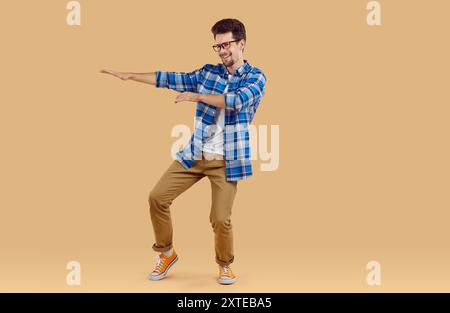 Porträt des lustigen brünetten Mannes in lässiger Kleidung, der fröhlich auf rosa Hintergrund tanzt. Stockfoto