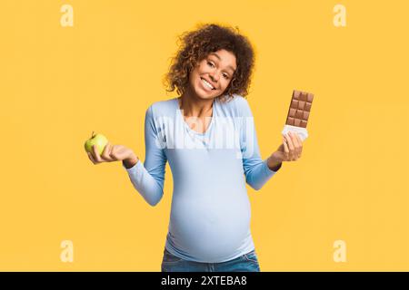 Schwangerschaft Ernährung. Schwangere Frau die Wahl zwischen Apple und Schokolade Stockfoto