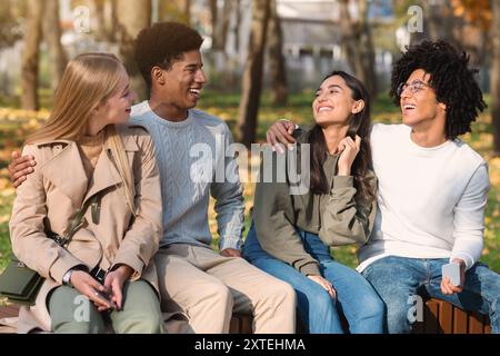 Gemischtes Rennen teen Paare sitzen auf Bank im öffentlichen Park Stockfoto