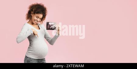 Sehen Sie hier! Angeregte afro-schwangere Frau mit Ultraschalluntersuchung Stockfoto