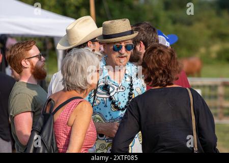 Abseits der Bühne beim Maverick Americana Musikfestival 2018 im ländlichen Suffolk Hank Wangford mit Strohhut, Sonnenbrille und hellem Hemd mit Freundinnen Stockfoto