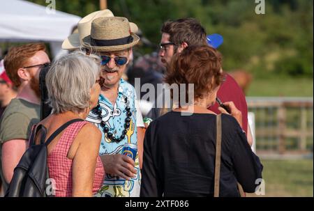 Abseits der Bühne beim Maverick Americana Musikfestival 2018 im ländlichen Suffolk Hank Wangford mit Strohhut, Sonnenbrille und hellem Hemd mit Freundinnen Stockfoto