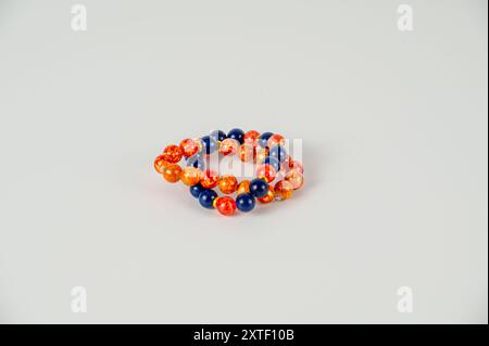 Ein Armband mit blauen und orangen Perlen. Das Armband besteht aus Glasperlen und ist auf weißem Hintergrund Stockfoto