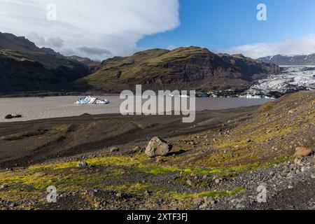 Solheimajokull, Teil des Myrdalsjokull-Gletschers, Gletscherlagune mit schwimmenden blauen Eisbergen und roher Berglandschaft, Island. Stockfoto