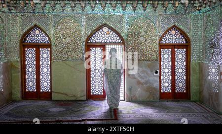 Shiraz, Iran - 4. Mai 2019: Unbekannte Frau im Schrein und Mausoleum von Shah-e-Cheragh, der Spiegelmoschee, in Grün mit zahlreichen Spiegeln dekoriert. Stockfoto