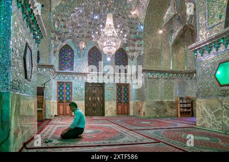 Shiraz, Iran – 4. Mai 2019: Muslimischer Mann betet im Schrein von Shah-e-Cheragh, der Spiegelmoschee, die in Grün mit zahlreichen Spiegeln dekoriert ist. Stockfoto