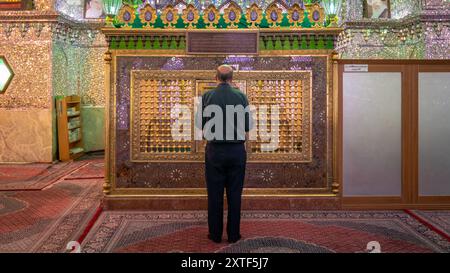 Shiraz, Iran – 4. Mai 2019: Muslimischer Mann betet im Schrein von Shah-e-Cheragh, der Spiegelmoschee, die in Grün mit zahlreichen Spiegeln dekoriert ist. Stockfoto