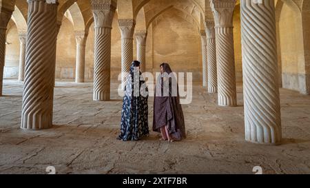 Shiraz, Iran - 4. Mai 2019: Zwei iranische Frauen sprechen im Gebetssaal der Vakil-Moschee mit Säulen. Vakil bedeutet Regent, Titel von Karim Khan, Gründer von Stockfoto